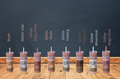 Row of colorful tumblers with various designs on a wooden surface and dark background