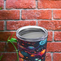 Biology-themed tumbler with cosmic design featuring planets and stars, ideal for science lovers. Vibrant, colorful tumbler placed on a wooden surface with greenery and a brick wall in the background, perfect for students and biology enthusiasts