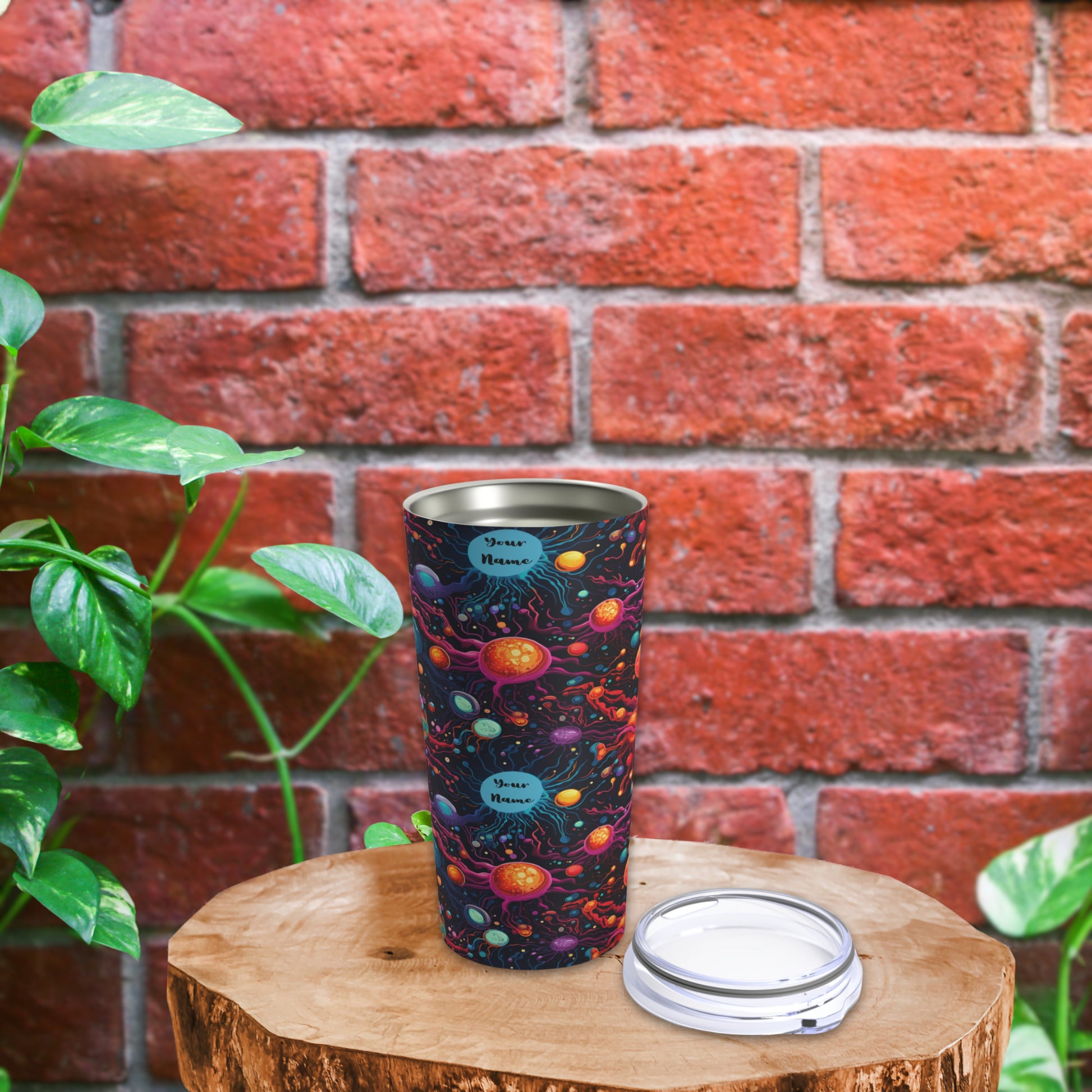 Biology-themed tumbler with cosmic design featuring planets and stars, ideal for science lovers. Vibrant, colorful tumbler placed on a wooden surface with greenery and a brick wall in the background, perfect for students and biology enthusiasts